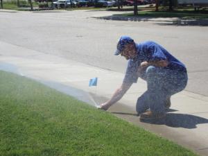 a Garland Sprinkler Repair team member checks a pop up head